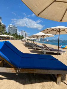 a row of beach chairs and umbrellas on a beach at Grands StarCity in Nha Trang
