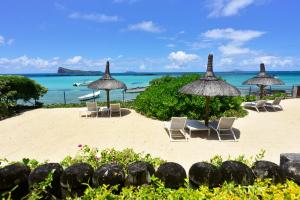a beach with chairs and umbrellas and the ocean at Coral Villa in Cap Malheureux