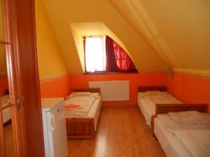 オロシュハーザにあるKertvárosi Vendégházのベッド3台と窓が備わる客室です。