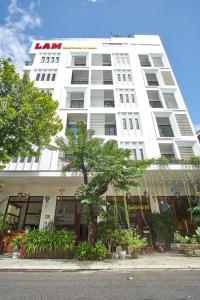 a white building with a tree in front of it at LAM Apartment & Hotel Danang - Quiet Living in Modern Comfort in Danang
