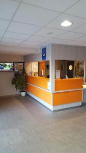 una sala de espera con un mostrador naranja en un edificio en Premiere Classe Sens Nord- Saint Clément en Sens