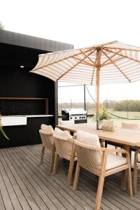 a wooden table with chairs and an umbrella on a deck at The Station Hunter Valley in Pokolbin