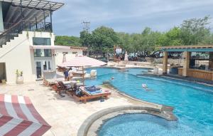 a large swimming pool with chairs and an umbrella at Pine Tree Beach Hotel in Gili Trawangan
