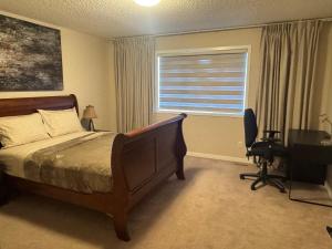 a bedroom with a bed and a desk and a window at Peace Home in Calgary