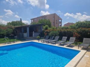 a swimming pool with chairs and a house at Villa Müller in Poreč