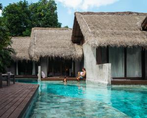 a woman and a child sitting in a swimming pool at RONJA Boutique Hotel - Adults Only in Uluwatu
