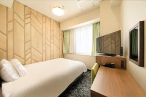 a hotel room with a bed and a flat screen tv at Hotel Nagano Avenue in Nagano