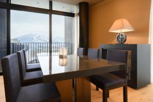a dining room with a table and chairs and a balcony at HOTELA Niseko Towers in Kutchan