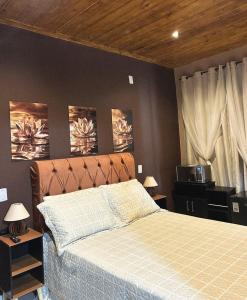 a bedroom with a bed and two paintings on the wall at Gruta do Pavão in Paraty