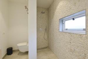 a bathroom with a toilet and a window at Follow The Sun Apartment in Zandvoort +7 photos
