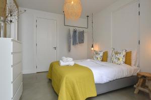 a bedroom with a bed with a yellow blanket at Follow The Sun Apartment in Zandvoort