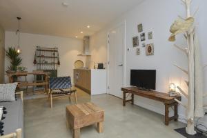 a living room with a television and a table at Follow The Sun Apartment in Zandvoort