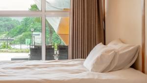 a bed with white pillows in front of a window at Mungyeong The Most Glamping in Mungyeong