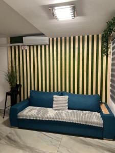 a blue couch in a room with a striped wall at Luxus Cluj Airport Apartments in Cluj-Napoca