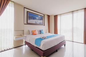 a bedroom with a large bed in a room with windows at SANS Vibes Hotel Igloo Cikarang in Cibitung