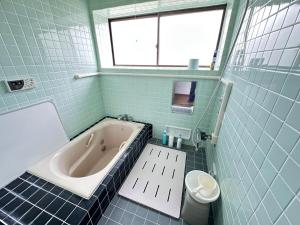 a blue tiled bathroom with a tub and a toilet at さくらもり in Nagano