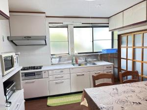 a kitchen with white cabinets and a table with chairs at さくらもり in Nagano