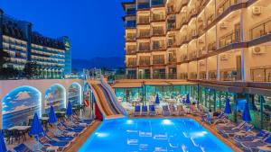 a hotel pool with chairs and a slide at Grand Barhan Hotel Alanya in Alanya