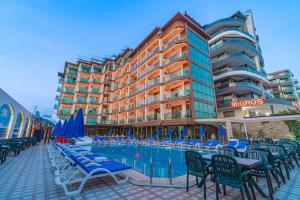 a hotel with chairs and a swimming pool in front of a building at Grand Barhan Hotel Alanya in Alanya