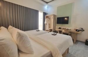 a hotel room with two beds and a desk at Pine Tree Beach Hotel in Gili Trawangan