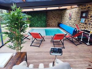 a patio with a pool and chairs and a table at Climatisation avec La Rouyonnaise in Tinténiac