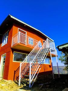an orange house with a staircase on the side of it at Pinaceae Resort in Chakrāta