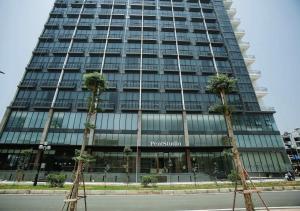 two palm trees in front of a tall building at PentStudio Westlake - Cozy Duplex - New Apartment in Hanoi