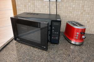 a microwave sitting on a counter next to a red toaster at Sri Apartment Homestay 2BHK Pondicherry A2 in Pondicherry +8 photos