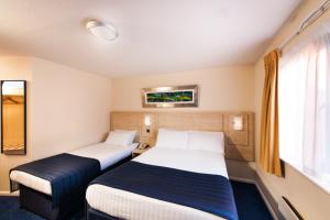 a hotel room with two beds and a window at Leonardo Inn Aberdeen Airport in Dyce