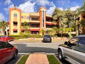 a parking lot with cars parked in front of a building at 1Dom Rep - Huge cozy 3 bedrooms - close to all transportation Jacobo Majluta - Residencial Paradise V Colina Arroyo 1 in Santo Domingo
