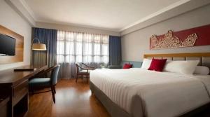 a hotel room with a large bed and a desk and a desk at Monopoli Hotel Bukittinggi in Bukittinggi