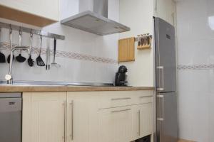 a kitchen with white cabinets and a stainless steel refrigerator at Brisa Chilches nº 5 in Málaga