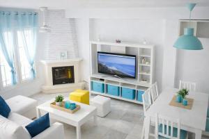 a white living room with a tv and a fireplace at Brisa Chilches nº 5 in Málaga