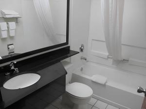 a bathroom with a toilet and a sink and a tub at Rodeway Inn & Suites Chandler - Phoenix South I-10 in Chandler