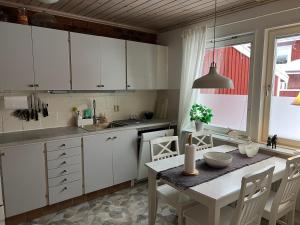 a kitchen with white cabinets and a table with chairs at Rymligt radhus in Borlänge