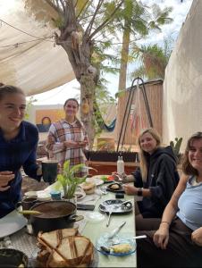 a group of people sitting around a table with food at The Shelter Hostel Eilat in Eilat +13 photos