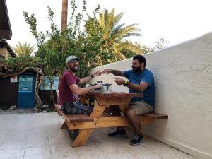 two men are sitting at a picnic table at The Shelter Hostel Eilat in Eilat