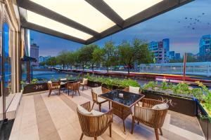 a patio with tables and chairs and a view of a river at Mercure Qingdao May Fourth Square in Qingdao