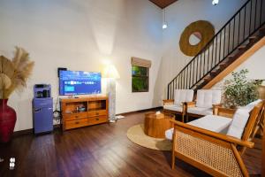 a living room with a television and a staircase at The Phalosaa Villa unit Family in Ngaglik