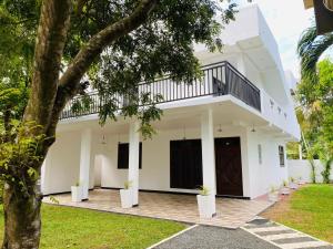 a white house with a tree in front of it at Wishwa Villa in Weligama
