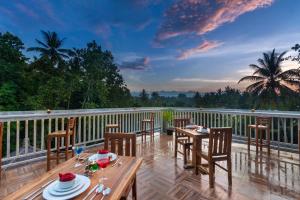 a deck with tables and chairs on a balcony at Coconut Boutique Resort in Senggigi 