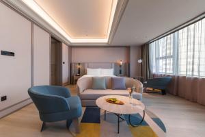 a hotel room with a bed and a couch and a table at Mercure Qingdao Coast in Qingdao