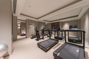 a gym with treadmills and ellipticals in a room at Mercure Qingdao Coast in Qingdao