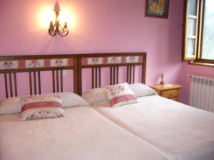 a bedroom with a white bed with two pillows at Casa Maseda in Villayón