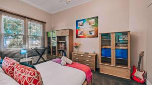 a bedroom with a bed and a guitar and a desk at Family Cottage in Bendigo