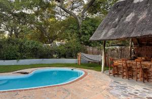 a resort with a swimming pool and a thatch roof at Pioneer Camp in Lusaka +15 photos