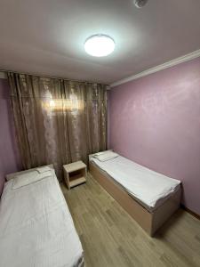 a bedroom with two beds and a purple wall at Гостиница"Hostel" in Karagandy
