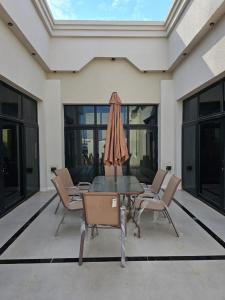 a table with chairs and an umbrella on a patio at شاليه العهد Al Ahad in Badīyah