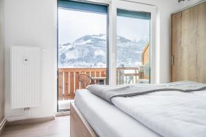 a bedroom with a bed and a large window at Praga Apartments & Restaurant Zell am See-Kaprun in Piesendorf