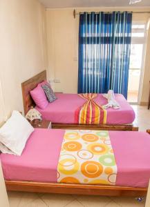 three beds in a room with pink and yellow at Chez Jenny port Mathurin in Rodrigues Island